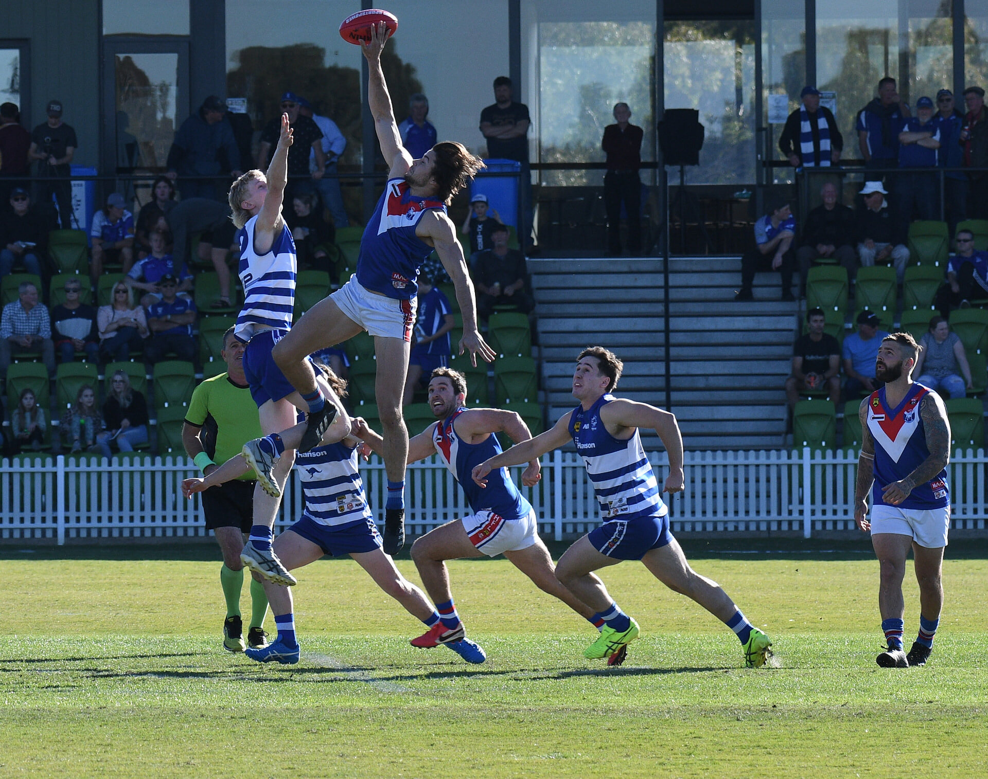 Hills Football League players contesting the ball in the air in front of the grandstand